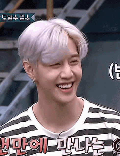 a man wearing a black and white striped shirt with korean writing on it smiles