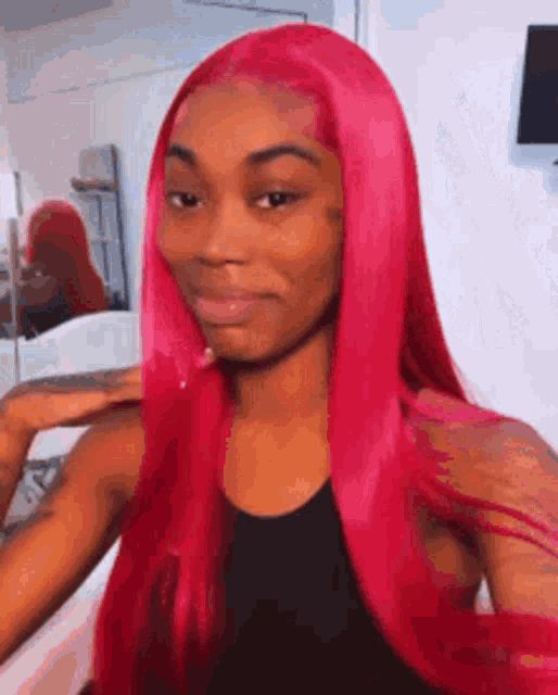 a woman with long red hair is making a funny face while wearing a black tank top .