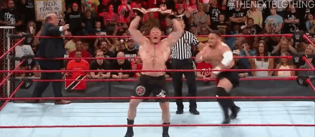 a wrestling match is being held in a ring with a referee .