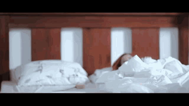 a woman is laying in a bed with white sheets