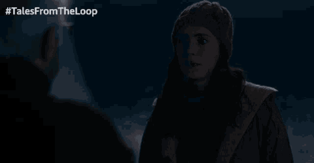 a man and a woman are looking at each other in a dark room with tales from the loop written above them