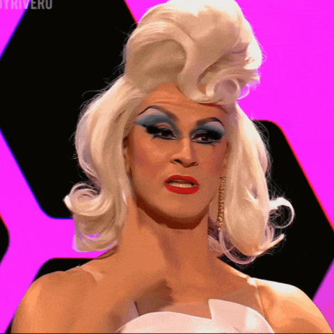 a drag queen with a white wig and blue eye shadow