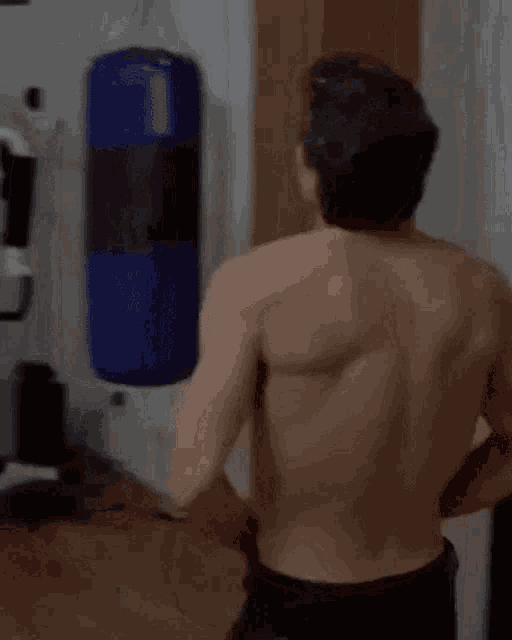 a shirtless man is standing in front of a closet and looking at something .