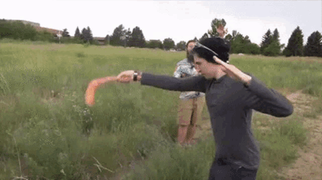 a man is throwing a frisbee in a field while another man looks on .
