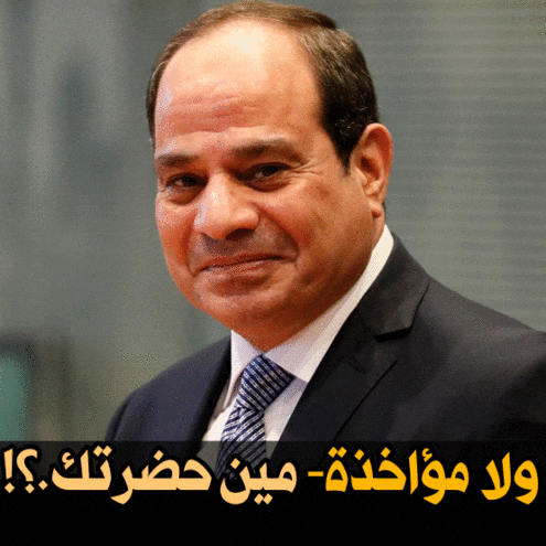 a man in a suit and tie is smiling with arabic writing behind him