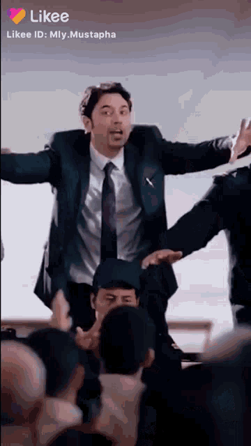 a man in a suit and tie is standing in front of a crowd with his arms outstretched