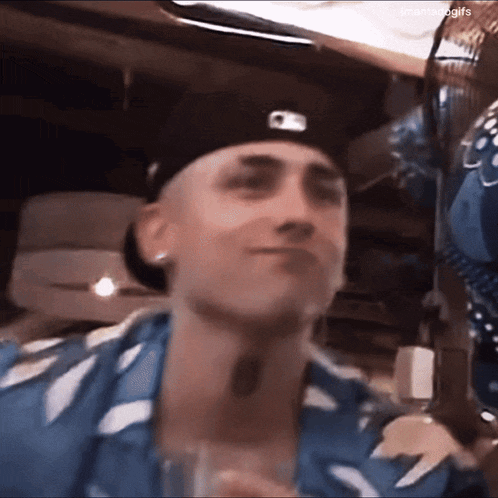 a man wearing a hat and a blue shirt is holding a glass
