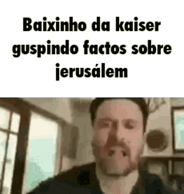 a man with a beard is standing in front of a window and talking .