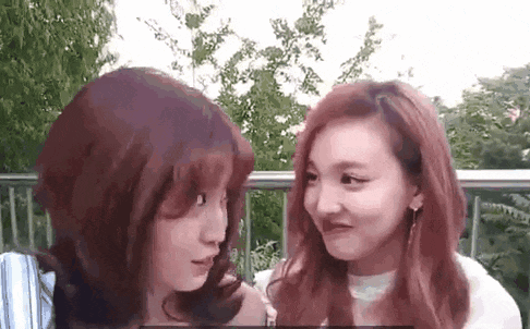 two young women are looking at each other and making funny faces .