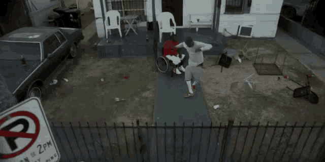 a man in a wheelchair is standing in front of a house with a bicycle .