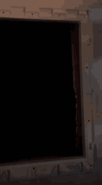 a man in a red shirt is peeking out of a window