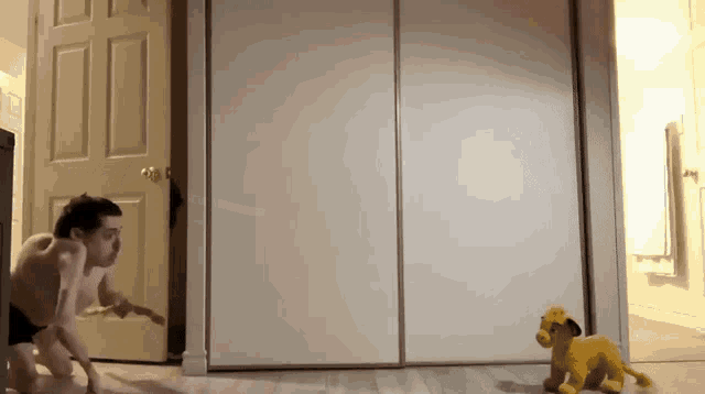 a shirtless man is playing with a stuffed lion in a room