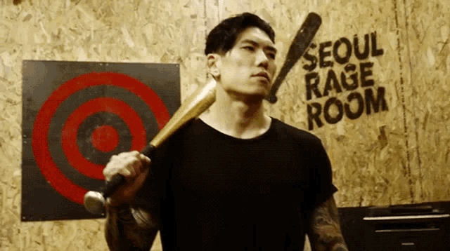 a man is holding a baseball bat in front of a sign that says seoul rage room