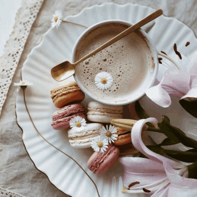 a cup of coffee sits on a plate with flowers and macarons
