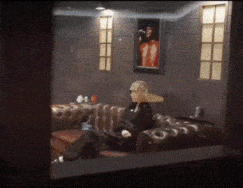 a woman in a hat sits on a couch in a room with a picture of michael jackson on the wall