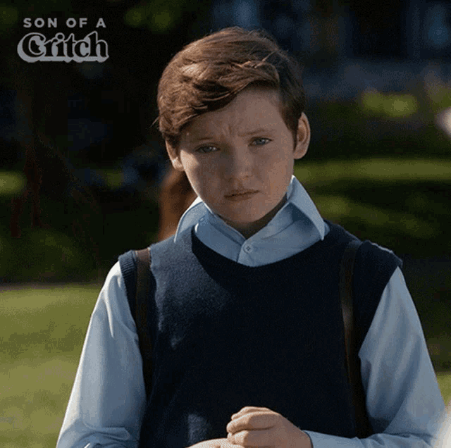 a young boy stands in front of a sign that says son of a critch