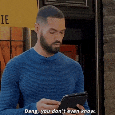 a man in a blue sweater holds a tablet and says dang you don 't even know