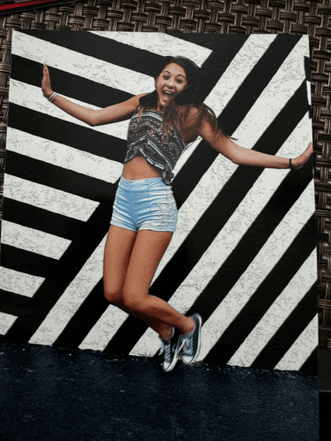 a girl jumps in front of a black and white striped background