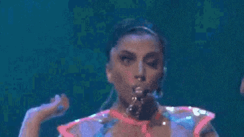 a woman in a pink top is dancing on a stage with a man behind her .