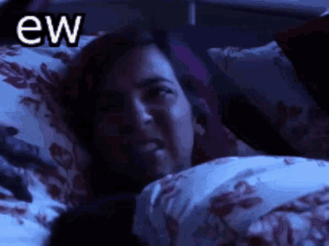 a woman is laying in bed with the word ew written above her