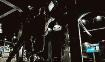 a man in a black suit is standing in a dark room .
