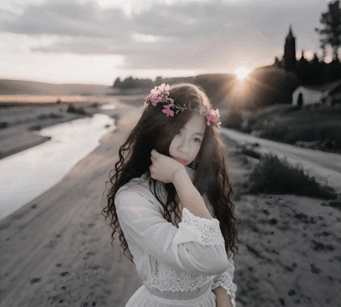 a woman with a flower crown on her head stands in front of a river