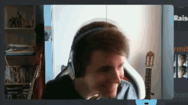 a man wearing headphones is smiling in front of a guitar in a room