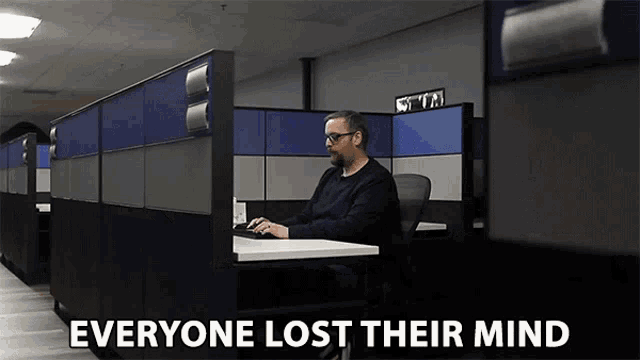a man sits in a cubicle with the words everyone lost their mind