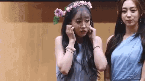 a woman wearing a flower crown is standing next to another woman wearing glasses .
