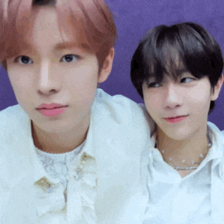 a couple of young men are standing next to each other on a purple background .