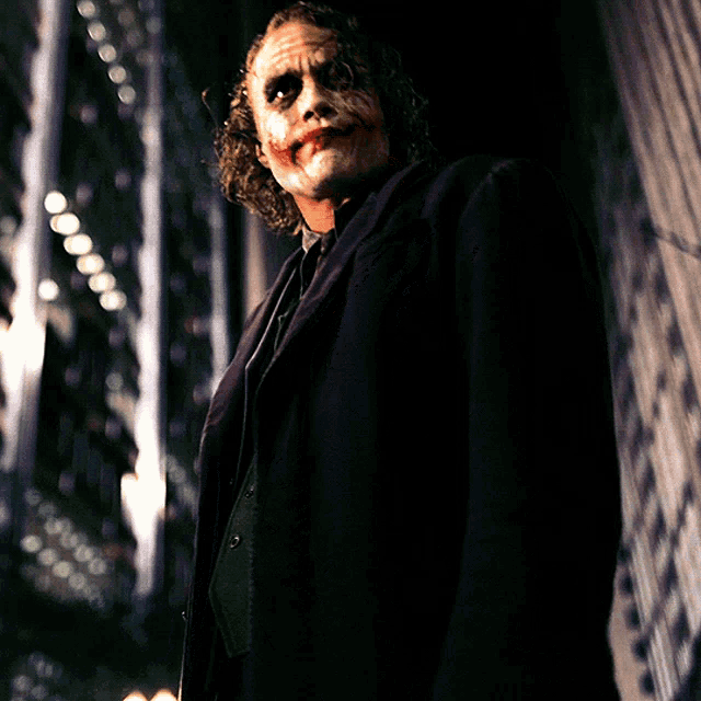 a man with a joker mask on his face is standing in a dark room