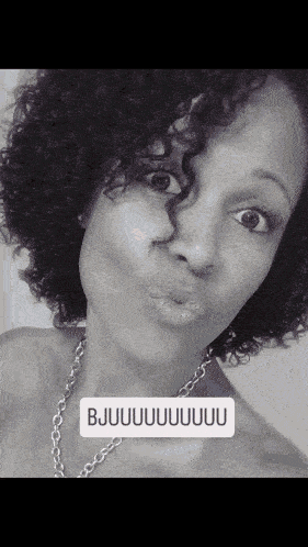a woman with curly hair is wearing a necklace and says bjuuuuuu