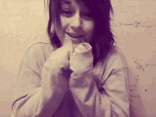 a girl with a nose ring is smiling in front of a wall with writing on it