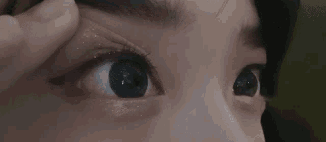 a close up of a woman applying eye shadow to her eye