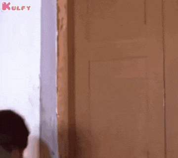 a man is standing in front of a door looking out of it .