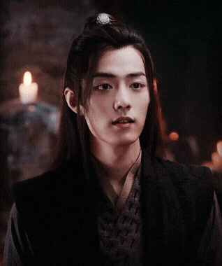 a man with long hair is standing in front of a candle with his eyes closed
