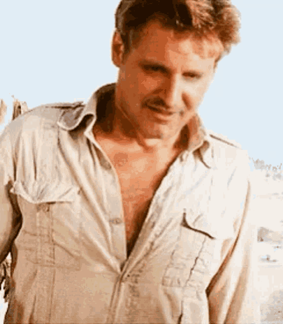 a man in a tan shirt is standing in the desert .