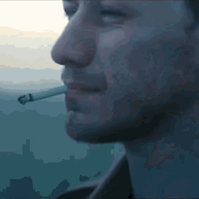 a close up of a man smoking a cigarette in his mouth