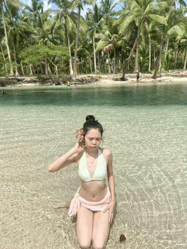 a girl in a bikini is kneeling in the water