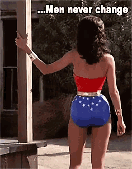 a woman in a wonder woman costume stands in front of a wooden post