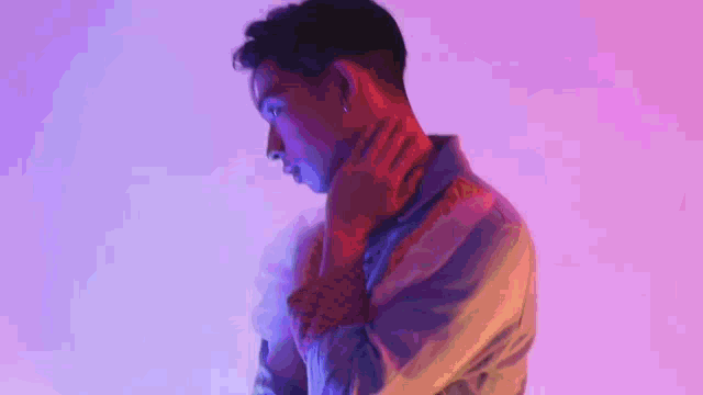 a man with a tattoo on his neck is standing in front of a purple wall .