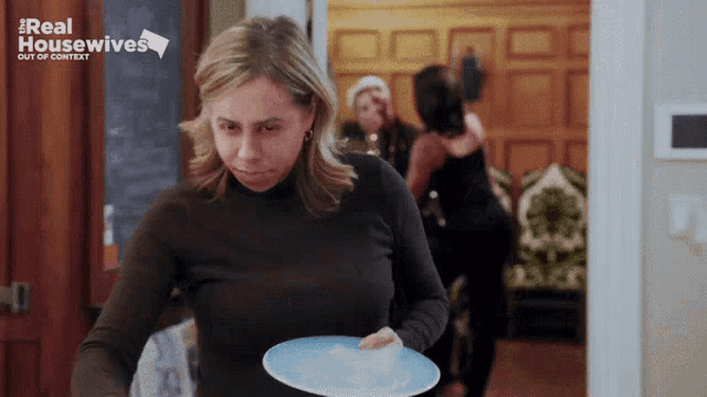 a woman is holding a blue plate with the words real housewives out of context on the bottom