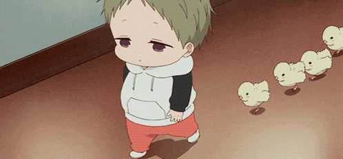 a little boy in a white and black hoodie walks next to a row of chicks