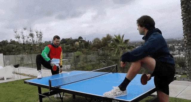two men are playing ping pong on a table that says wilson