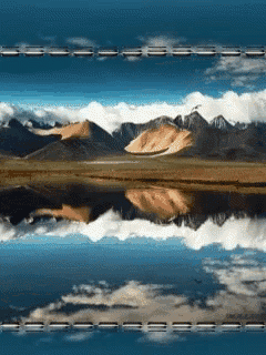mountains are reflected in a body of water with a blue sky