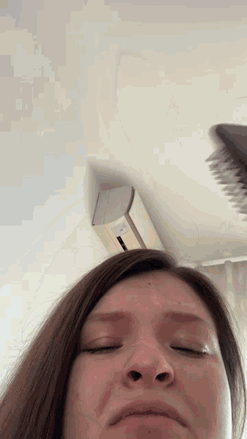 a woman with her eyes closed brushes her hair