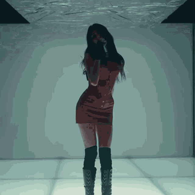 a woman in a red dress is singing into a microphone in a dark room