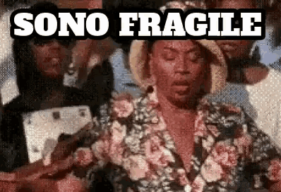 a man in a floral shirt is standing in front of a group of people with the words sono fragile above him .