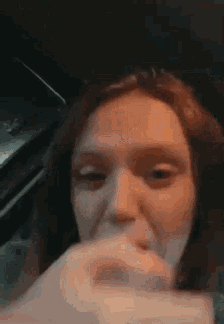 a woman is sitting in a car with her mouth open .