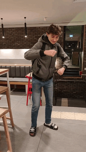 a young man wearing a gray jacket and blue jeans